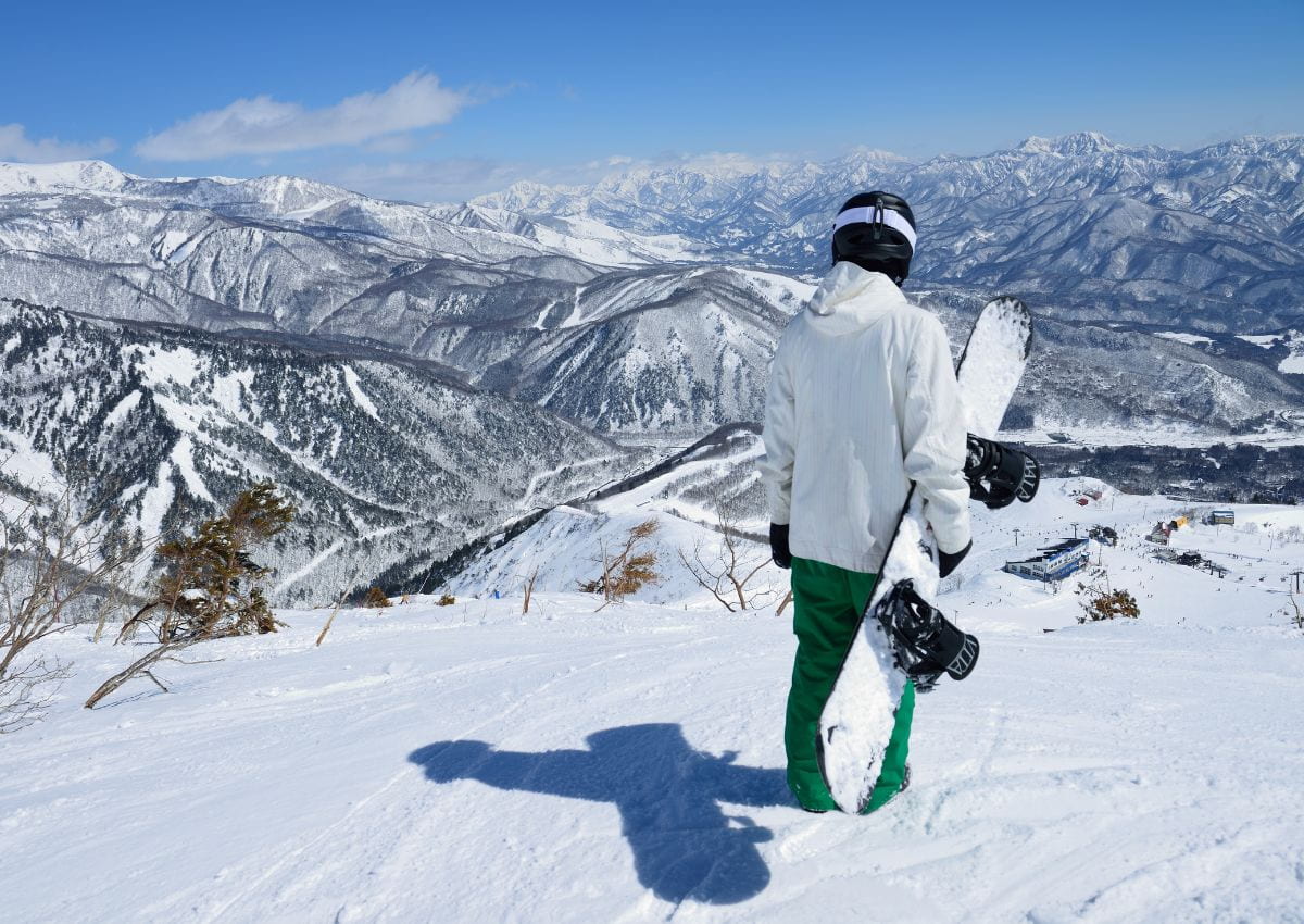 Snowboarder blickt auf eine verschneite Winterlandschaft in Hakuba, Japan
