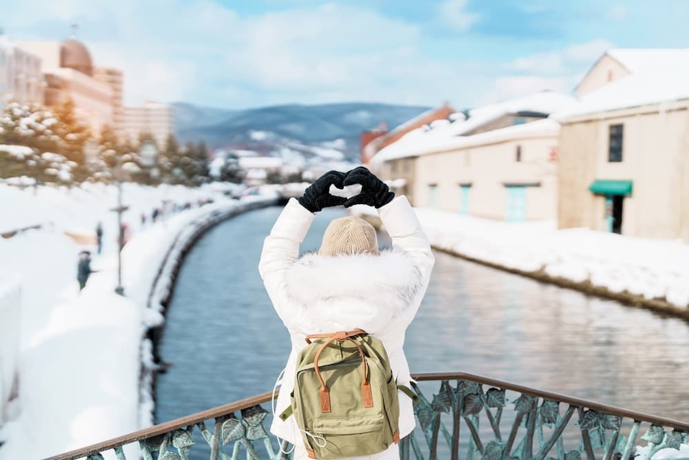 Touristen beim Sightseeing entlang des verschneiten Otaru-Kanals in Hokkaido, Japan, und geniessen die Wintersaison