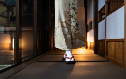Frau im Kimono geht durch einen traditionellen Ryokan mit Tatami-Matten und Shoji-Türen